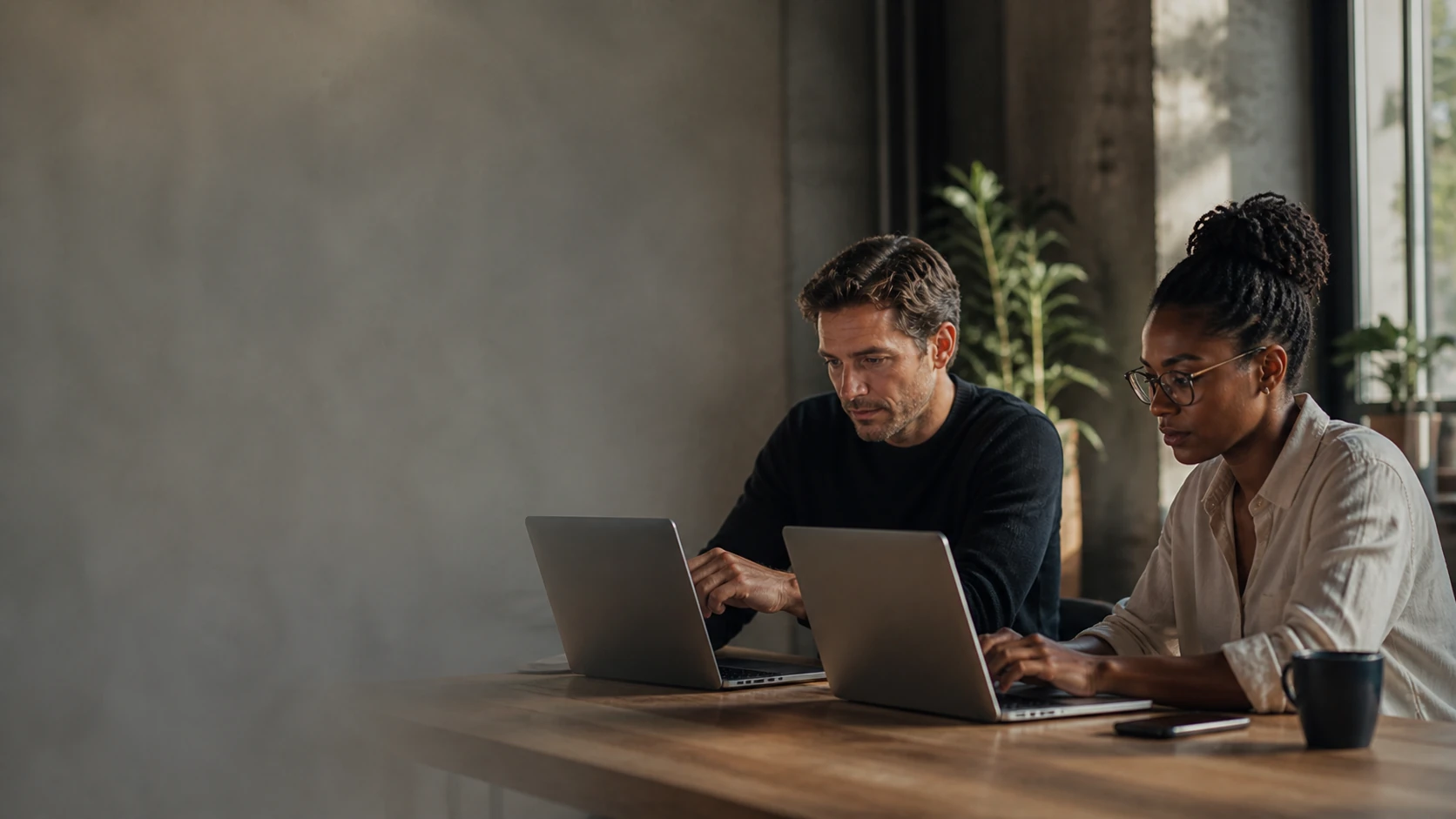 Two colleagues working together on laptops in a startup office.